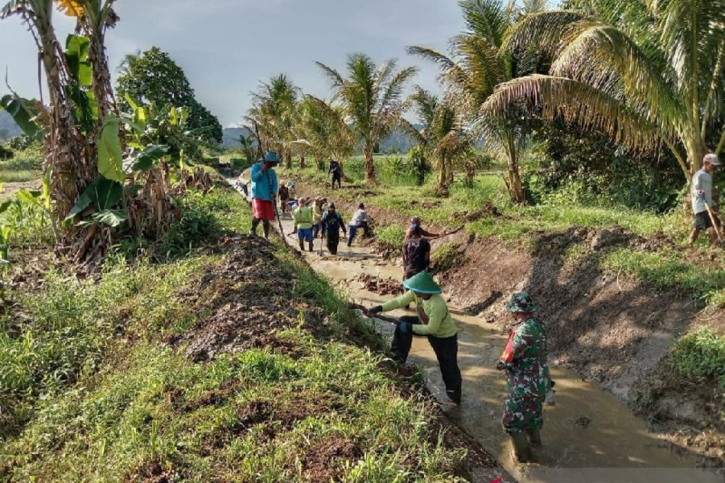 Soldiers and villagers clearing mud from an irrigation channel between fields