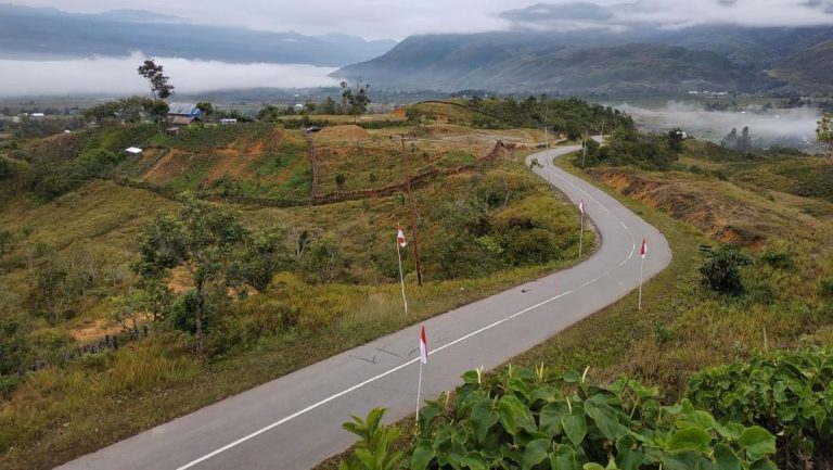 A paved winding road on the Trans-Papua Highway passing through the mountainous landscape of Papua’s Central Highlands.