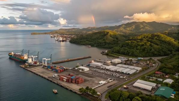 A major shipping port and container terminal in Papua surrounded by ocean and green hills under a sunset sky