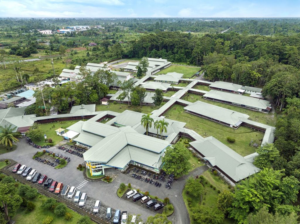 Aerial view of a hospital complex with low buildings surrounded by trees
