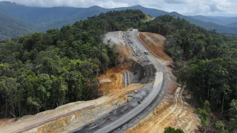 Aerial view of a new road cut through forested hills
