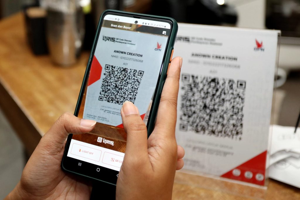 Hand holding a phone to scan a payment QR code.