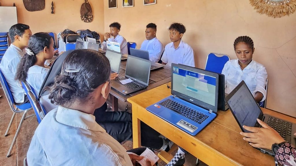 Students working on laptops at desks in a classroom.