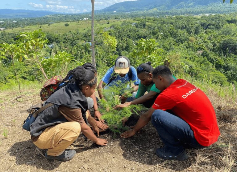 Young people planting tree seedlings on a hillside.