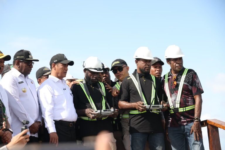 Officials and workers in hard hats and safety vests at an outdoor site.