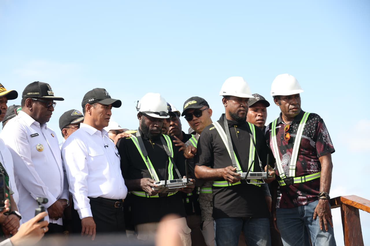 Officials and workers in hard hats and safety vests at an outdoor site.