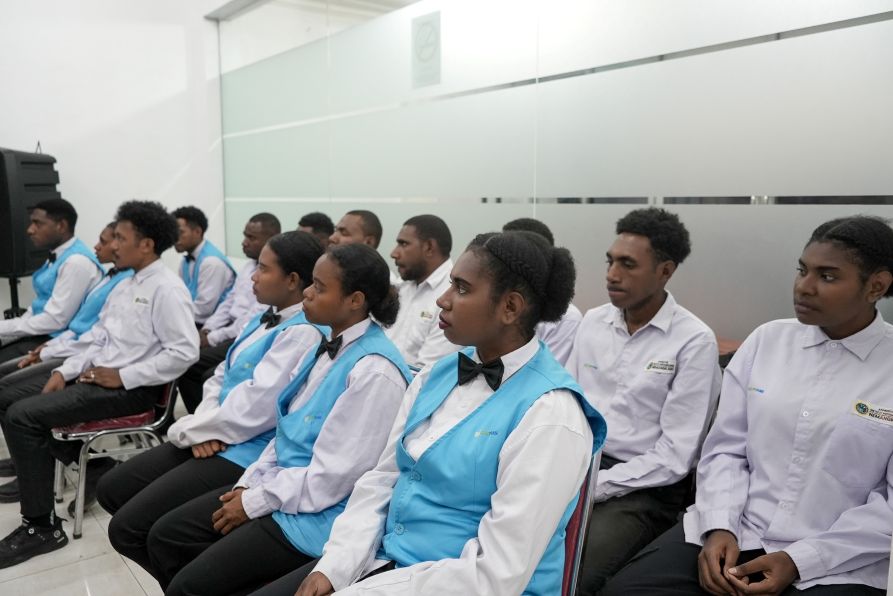 Young trainees in hospitality uniforms seated in a training room.