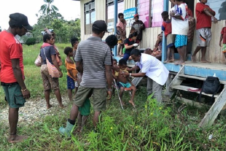 Health workers examining villagers outside a village health post.