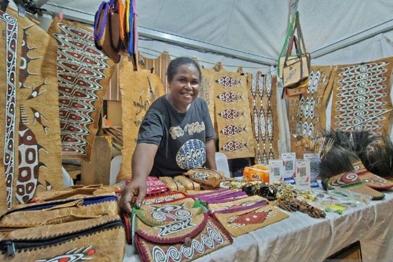 Woman selling handmade bags and crafts at an exhibition stall.