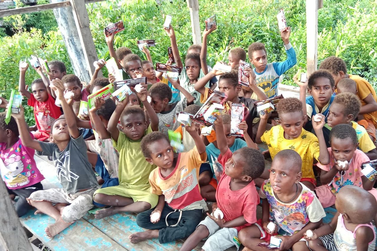 Children holding up milk cartons at a village gathering.