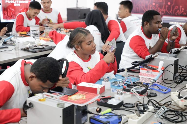 Young trainees practising electronics repair at a vocational workshop.