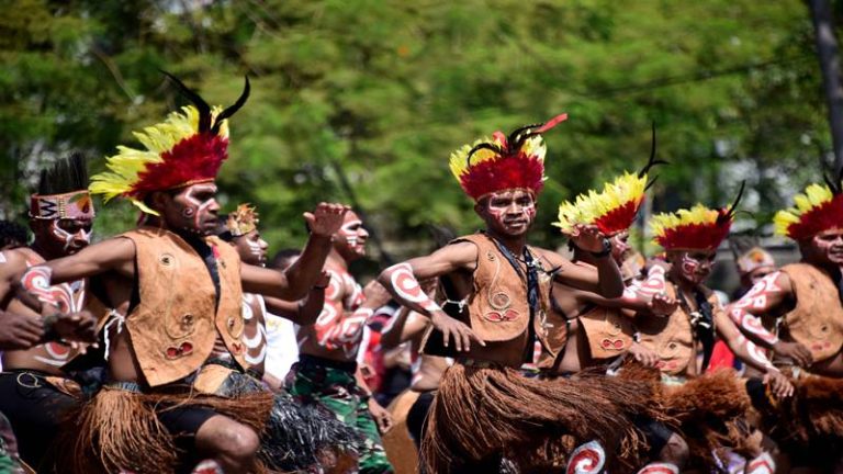 Papuan dancers in feathered headdresses performing a traditional dance.