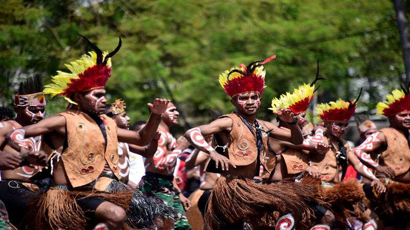 Papuan dancers in feathered headdresses performing a traditional dance.