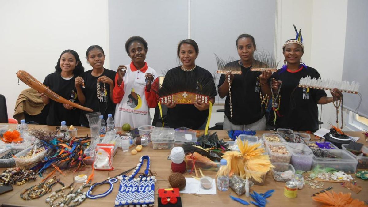 Young Papuan women displaying handmade crafts and souvenirs on a table.