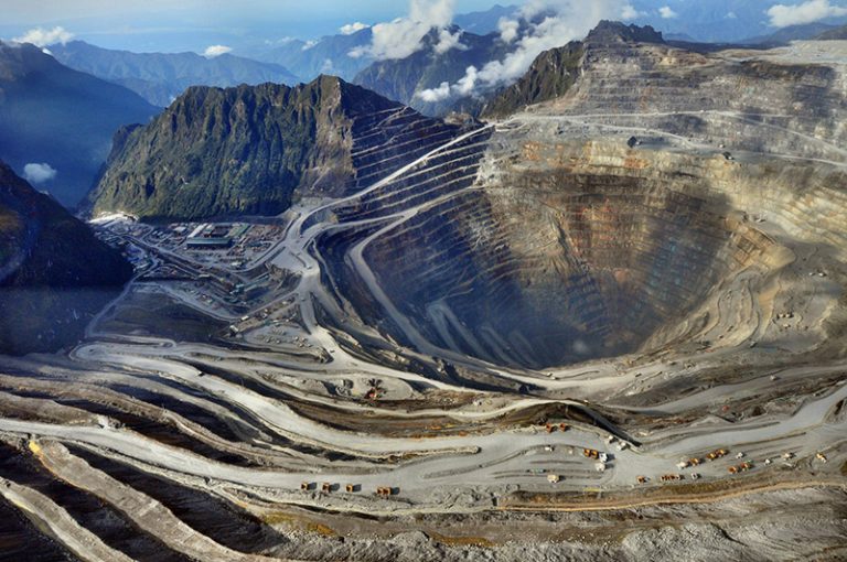Aerial view of the terraced open pit of the Grasberg copper and gold mine surrounded by mountains in Mimika, Papua