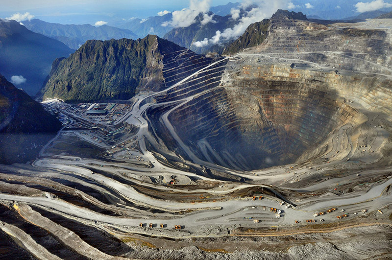 Aerial view of the terraced open pit of the Grasberg copper and gold mine surrounded by mountains in Mimika, Papua