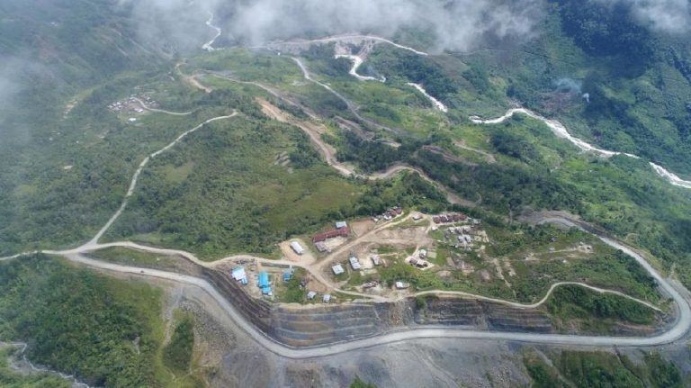 Aerial view of a winding road cutting through green mountains.