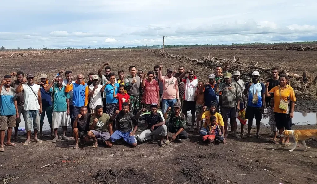 Large group of residents posing on a cleared field.
