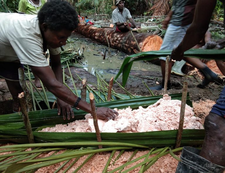 People processing sago pith on palm-leaf mats.