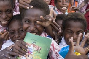 Smiling schoolchildren in Kokonao, Mimika Regency, Papua, holding a school exercise book