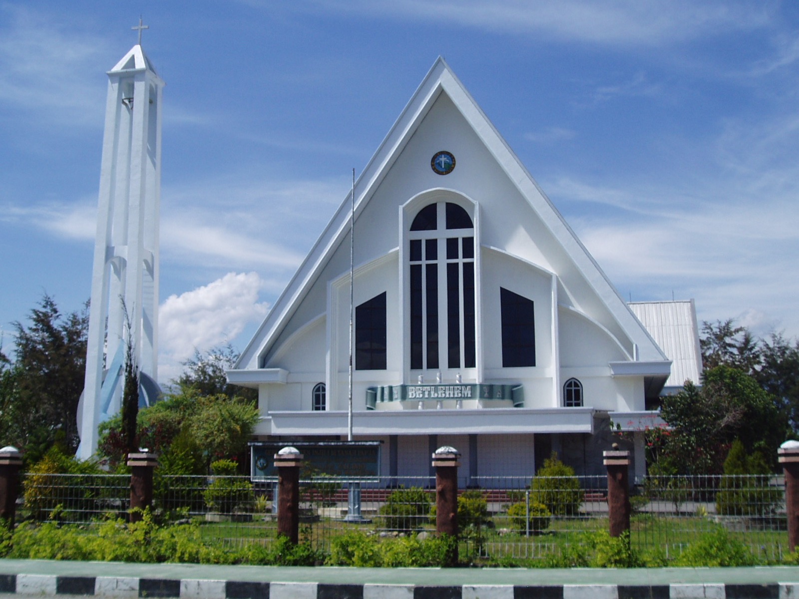 White Betlehem church with a tall bell tower in Wamena under a blue sky