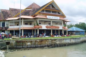 Port of Sorong passenger terminal with a red-roofed building and people waiting by the water